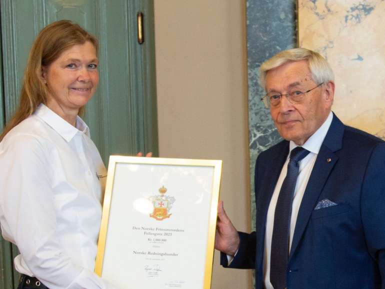 Ordenens Stormester Ragnar Tollefsen overrekker gaven til Norske Redningshunders leder Mette Kiær Sørensen